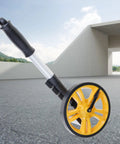 Measuring Wheel 0-9999.9m Digital Display for Construction Worker with a yellow wheel on an outdoor surface.