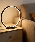 Open Circle LED Table Lamp With Dimmable Touch Control And Warm 3000K Light in Black on nightstand in bedroom, modern minimalist design