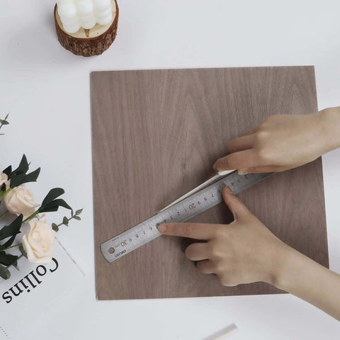 Walnut unfinished wood board, 12x12 inches, 3mm thick, being measured with a metal ruler