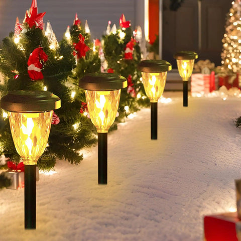 Snowy path with decorative solar lights and festive Christmas trees with red bows