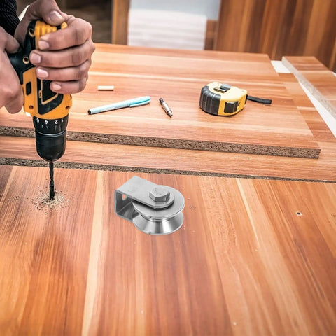 Close-up of a Heavy Duty Stainless Steel Pulley Wheel Track Roller For Sliding Doors And Gates Built Different With Zero Noise Vibes Smooth Glide Performance Handles Heavy Loads On Wire Rope Systems Top Tier, being drilled into wooden surface.