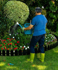 Person watering plants beside 5.5 Inch Tall Garden Edging Border Kit With 20 Feet Of Flexible Plastic Border for Lawns, Yards, and Flower Beds