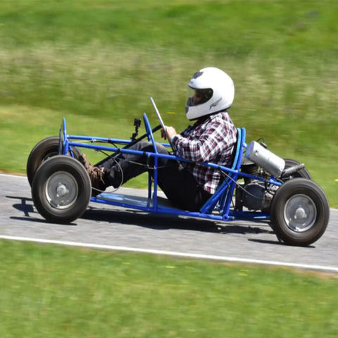 Person driving a blue go kart on a track, showcasing the Premium 4X4 Go Kart Live Axle Hubs 2 Pack.