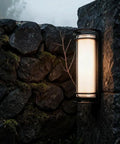 ROPCVAX Led Wall Sconce Lighting Fixture Lamp Modern Minimalist Aluminum Black mounted on stone wall, providing soft illumination.