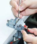 Mini Jeweler Table Clamp For Hobbyists And Pros Portable Workbench Vise With Secure Grip Durable Metal Construction Ideal Jewelers Clamp For Jewelry Making And Craft Repairs On The Go being used by hands on a white table