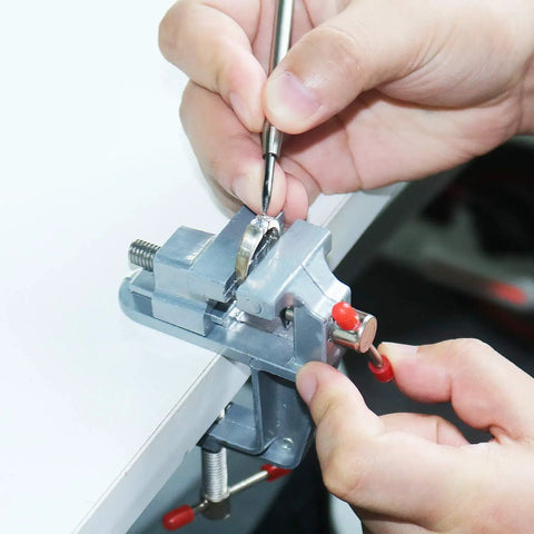 Mini Jeweler Table Clamp For Hobbyists And Pros Portable Workbench Vise With Secure Grip Durable Metal Construction Ideal Jewelers Clamp For Jewelry Making And Craft Repairs On The Go being used by hands on a white table