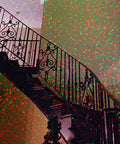 Motion Laser Holiday Projector with thousands of lights creating red and green patterns on staircase railing indoors