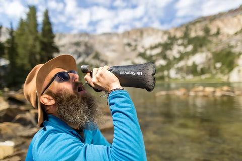 Person using Peak Series Collapsible Water Filter Bottle 1L Squeeze Hydration System For On The Go Trail Running Camping Hiking Travel