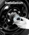 Installed view: silver trailer wheel hub grease cover being fitted to a black steel trailer wheel