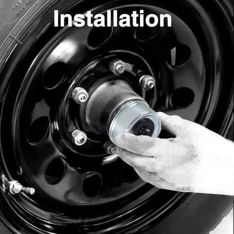 Installed view: silver trailer wheel hub grease cover being fitted to a black steel trailer wheel