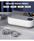 Totally Slick Portable Ultrasonic Cleaner For Sparkling Jewelry And Flawless Eyeglasses Hella Efficient Rechargeable Cleaning Pod For Retainers And Watches You Are Gonna Love on a wooden surface with eyeglasses and a watch nearby.