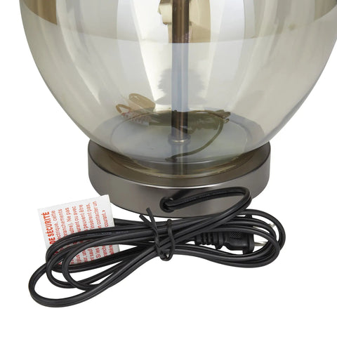 Close-up of glass body and iron base of Glass Table Lamp With Drum Shade In Champagne Finish, 17 By 17 By 27 Inches, with power cord.