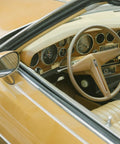 Automotive interior view of a vintage tan car with a wood‑grain dashboard and beige steering wheel