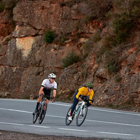 Cyclists on a road using Edge 1050 Premium Cycling Computer Bundle With Color Touchscreen Built In Speaker Training And Group Rides Road Alerts Silicone Case Screen Protectors Tether And More For Real Riders, showcasing in-action use.