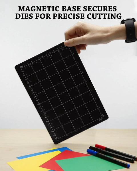Person holding Pro Grade Magnetic Die Cutting Shim 9x6 Inch with Grid, shown with colored paper and pens for crafting.