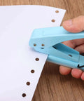 Hand using One Quarter Inch Hole Punch Handheld Heavy Duty Metal Paper Punch for tags, DIY projects, scrapbook, tickets, ergonomic blue grip
