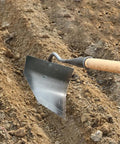 Workhorse Triangle Hoe Garden Tool With Hardened Steel Plow Head in soil, used for digging, weeding, and planting.