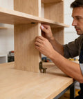 Man installing Rock Solid Steel Shelf Pins, Slick Bronze Plated 1/4 Inch Pegs on wooden shelves in a workshop.