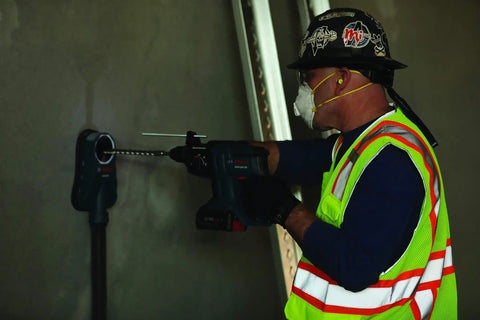 Worker using Dust Collection Attachment For SDS Max Hammer Drill With Dual Air Chambers And Wall Suction, drilling into wall.