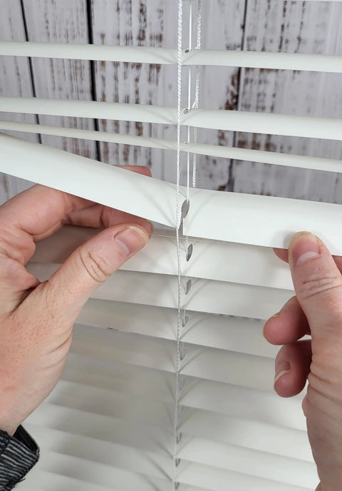 Easy DIY Slick Fix For Cracked Horizontal Blinds Clear Mini Slat Repair Kit With String Holes and Solid Tabs being applied to blind slats.