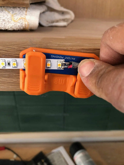 Magnetic Soldering Jig With Nano Suction Base holding LED strip for wiring on a wooden surface.