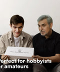 Two people holding a watch repair kit box labeled '155 Piece Watch Repair Tool Kit' perfect for hobbyists or amateurs.