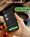 Person holding smartphone showing food ordering app interface in kitchen setting with missing ingredients message