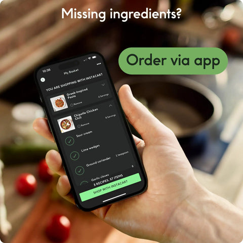 Person holding smartphone showing food ordering app interface in kitchen setting with missing ingredients message