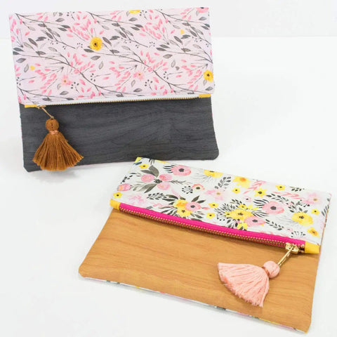 Two floral fabric clutches with tassels, one black and pink, the other yellow and pink, on a white background.