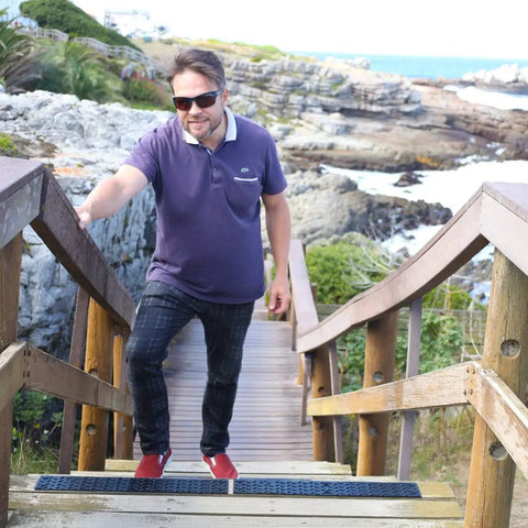 Man walking down stairs with Non Slip Outdoor Stair Treads 4x24 Inch Diamond Textured Rubber Mats for Steps visible.