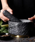 Hands using Granite Mortar And Pestle Set With Gold Metal Base 2 Cup Capacity For Making Fresh Guacamole Salsa Pesto.