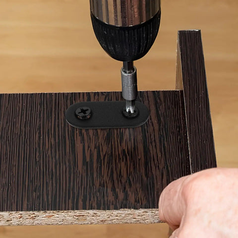 Drilling 12 sets black stainless steel flat mending brackets with screws for cabinets and furniture repair on wood surface