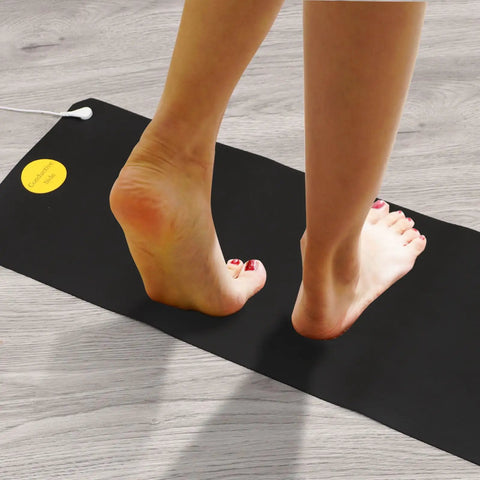 Person standing on Grounding Bed Mat With No Slip Bottom And Tangle Free Cord For Better Sleep Pain Relief Circulation Boost Reduced Inflammation And Calm 26.7x9.8 In 2 Pack For Home Office Meditation, showing feet in close-up