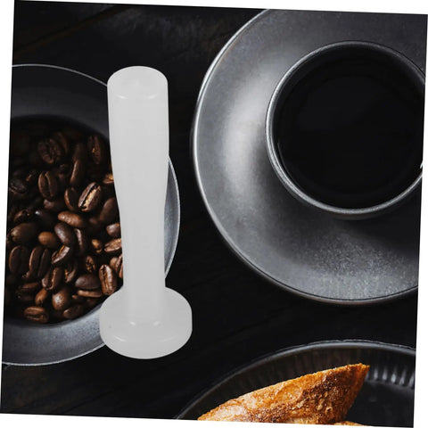 White Plastic Espresso Tamper For Home And Commercial Coffee Making No Frills Durable Press Tool surrounded by coffee beans