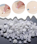 Assorted white plastic hole plugs in four sizes for cabinets and furniture, shown in use sealing screw holes
