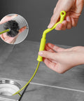 Flexible Drain Snake For Kitchen Sink And Bath Plumbing Portable Bendable Pipe Cleaner Spiral Design, hand holding pipe cleaner near sink.