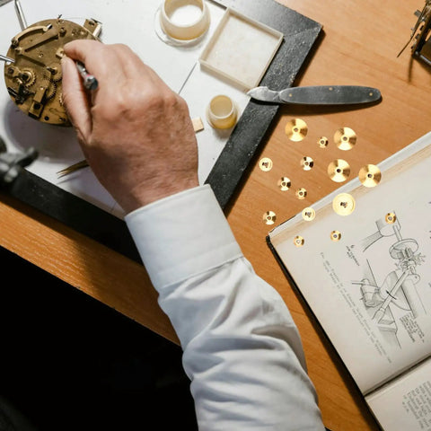 Man working on clock mechanism with Brass Clock Hand Nuts Set, 15 Pieces, Three Sizes 5mm 6mm 10mm OD, tools, and manual on desk.