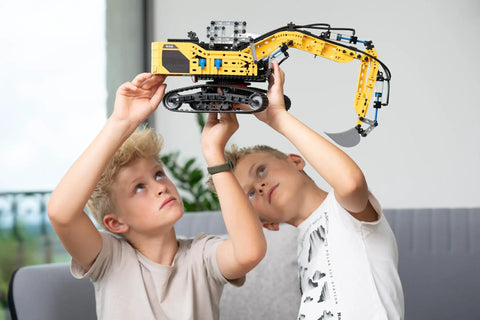 Liebherr R938 Pneumatic Excavator Kit 689 Piece Realistic Builder Model With Pneumatic System Manual Valves And Flow Regulators Ideal For Gearheads 10 And Up Great For Kids Teens And Adults Who Love Engineering. boys hold yellow excavator model