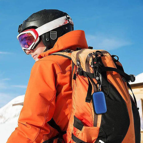 Man in orange jacket with black helmet and goggles carrying Portable Clamshell Electronic Organizer Case For Earbuds Headphones And Chargers.