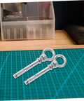 Stainless Steel Eye Bolts Hanger Kit For Heavy Duty Lifting And Hanging Expansion Bolts With Snap Hooks Five Piece Set For Pro Grade Secure Rigging Gear Racks And Hardware Projects, two stainless steel expansion eye bolts on cutting mat