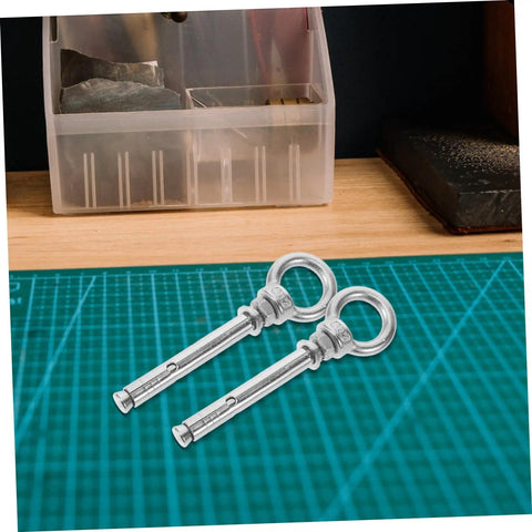 Stainless Steel Eye Bolts Hanger Kit For Heavy Duty Lifting And Hanging Expansion Bolts With Snap Hooks Five Piece Set For Pro Grade Secure Rigging Gear Racks And Hardware Projects, two stainless steel expansion eye bolts on cutting mat