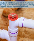 Close-up of red mechanical end-of-pipe gripper plug atop white PVC pipe joint (2 in and 1-1/2 in).