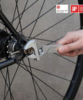 Close-up of an adjustable wrench being used on a bicycle wheel, demonstrating versatility in the 16 Piece Home Tool Kit With Storage Box Essential Hand Tools Set Including Screwdriver Wrench Hammer Tape Measure Pliers Great For Home Garage Office Dorm Repairs And DIY Projects.