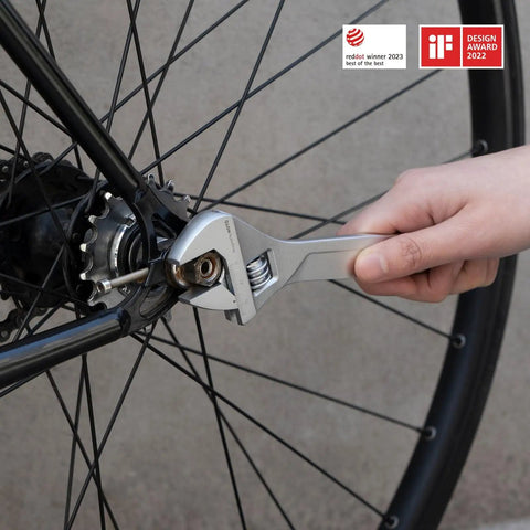 Close-up of an adjustable wrench being used on a bicycle wheel, demonstrating versatility in the 16 Piece Home Tool Kit With Storage Box Essential Hand Tools Set Including Screwdriver Wrench Hammer Tape Measure Pliers Great For Home Garage Office Dorm Repairs And DIY Projects.
