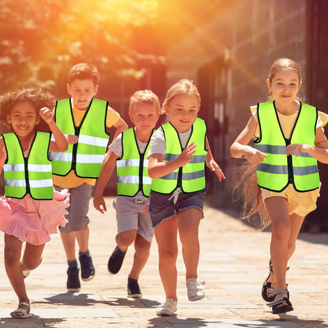 Children playing outdoors wearing Kids Reflective Safety Vest 20 Pack High Visibility Neon Vests with Zipper for Ages 3 to 10 in daylight.