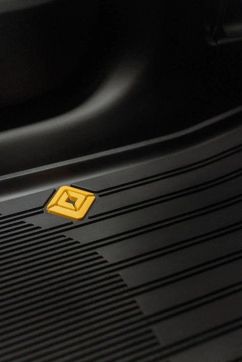 Close-up of grippy antislip base on Custom Fit Three Piece All Weather Floor Mats For Rivian R2 with yellow logo detail.