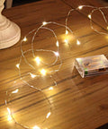 1 Pack Battery Powered Copper Wire Starry Fairy Lights With 50 LEDs And 16ft Of Warm White Glow on wooden table