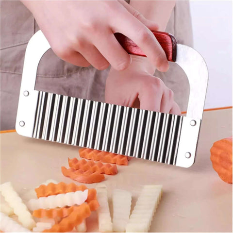 Handheld stainless steel crinkle cutter with red handle, front view cutting vegetables