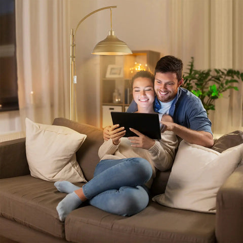 Dope Industrial Floor Lamp With Gold Finish For Rustic Farmhouse Style Arc Standing Lamp next to couple on sofa in living room.