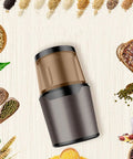 No Brainer Portable Bean To Cup Coffee Grinder And Spice Mill With Tap Control Quick Crushing Action Stainless Steel Bin viewed from above surrounded by spices.